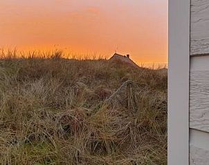 Adembenemende zonsondergang bij Strandjutter G2, chalet in Buren, Ameland, met uitzicht op de duinen.