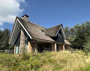 Rieten dak van vakantiehuis MIEKIE in Buren, Ameland, omgeven door gras en bomen.