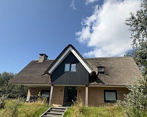 Hoofdingang van vakantiehuis MIEKIE in Buren, Ameland met houten trap en groene omgeving.