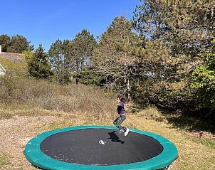 Kind speelt op trampoline bij vakantiehuis MIEKIE in Buren, Ameland, omringd door bomen.