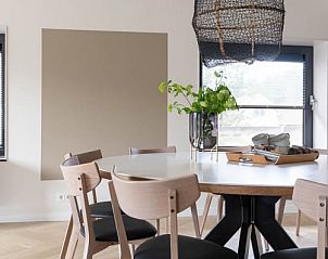 Moderne eetkamer in vakantiehuis MIEKIE, Buren, Ameland met houten vloer en designlamp.