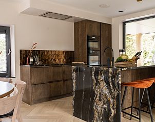 Stijlvolle keuken in vakantiehuis MIEKIE, Buren, Ameland met marmeren werkblad en houten kasten.