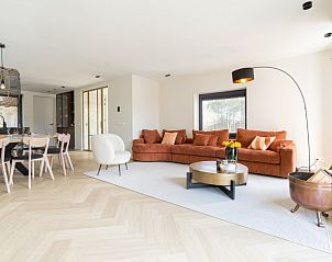 Open woonkamer in vakantiehuis MIEKIE, Buren, Ameland met oranje bank en eethoek.