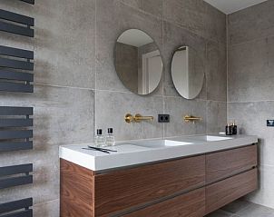 Moderne badkamer in vakantiehuis MIEKIE, Buren, Ameland met houten kast en stijlvolle spiegels.