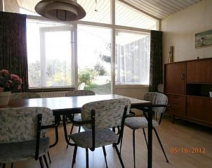 Eethoek in Bungalow Dolfijn, Buren, Ameland met grote ramen en uitzicht op de tuin.