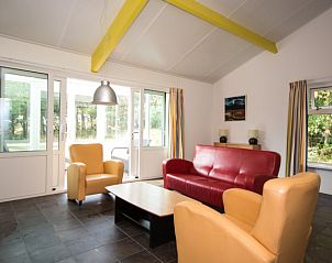 Lichte leefruimte in Bungalow 18, Buren, Ameland met comfortabele zitplaatsen en grote ramen.