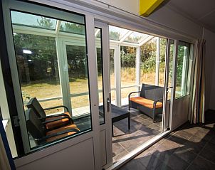 Zonnige serre van Bungalow 18 in Buren, Ameland met uitzicht op de natuurlijke omgeving.
