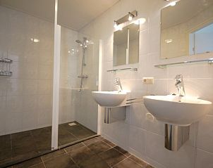 Stijlvolle badkamer in Bungalow 18, Ameland met dubbele wastafels en ruime douche.