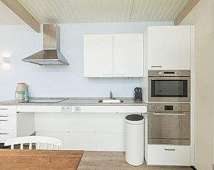 Moderne Kche im Ferienhaus Wadden Special in Hollum, Ameland, mit schlichten weien Schrnken und Gerten aus Edelstahl.