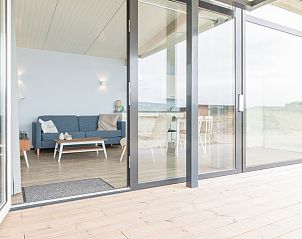 Modernes Wohnzimmer des Wadden Special Ferienhauses in Hollum, Ameland mit Glasschiebetren und Blick auf die Watteninseln.