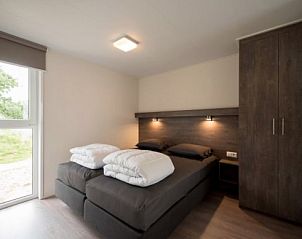Restful bedroom in AMELANDLODGE 4, vacation home in Hollum, Ameland, overlooking the natural surroundings.