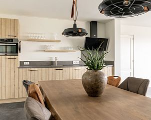 Open keuken in Langsdeel appartement, Hollum, Ameland, met houten kasten en moderne apparatuur.