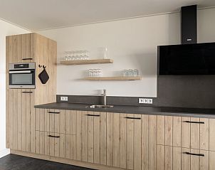 Moderne keuken in Langsdeel appartement, Hollum, Ameland, met houten afwerking en inbouwapparatuur.