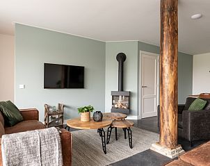 Stijlvolle woonkamer in Langsdeel appartement, Hollum, Ameland, met flatscreen-tv en open haard.