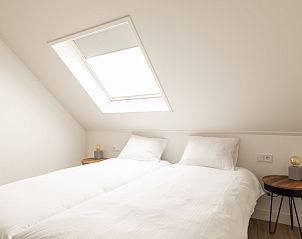 Lichte slaapkamer in Langsdeel appartement, Hollum, Ameland, met dakraam en comfortabele bedden.