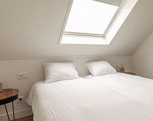 Gezellige slaapkamer in Langsdeel appartement, Hollum, Ameland, met wit beddengoed en houten nachtkastjes.