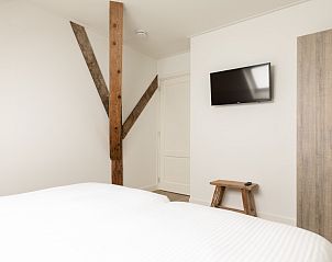 Slaapkamer met tv in Langsdeel appartement, Hollum, Ameland, met houten details en moderne inrichting.