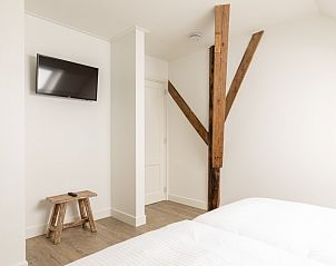 Slaapkamer in Langsdeel appartement, Hollum, Ameland, met houten balken en moderne meubels.