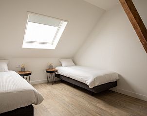 Ruime slaapkamer in Langsdeel appartement, Hollum, Ameland, met twee eenpersoonsbedden en dakraam.