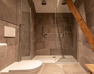 Moderne badkamer in Langsdeel appartement, Hollum, Ameland, met inloopdouche en houten details.