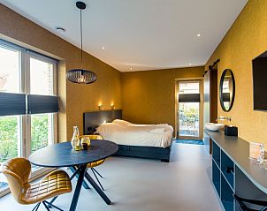 Lichte leefruimte in Breeze 1 appartement, Hollum, Ameland, met uitzicht op de tuin en comfortabele zitplaatsen.