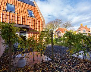 Gezellige tuin van Breeze 1 appartement, Hollum, Ameland, met zitjes en groene beplanting.