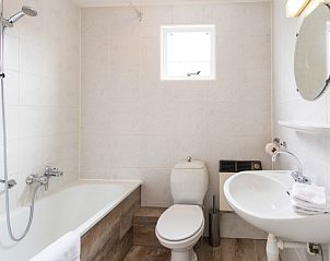 Moderne badkamer met bad en douche in Zilverschoon appartement, Hollum, Ameland, voor ontspanning na een dagje strand.