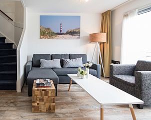 Ruime woonkamer in Wad appartement, Hollum, Ameland met gezellige bank en kunstwerk van de Waddeneilanden.
