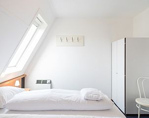 Lichte slaapkamer in Wad appartement, Hollum, Ameland met knusse inrichting en uitzicht op de natuur.