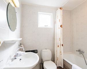 Moderne badkamer in Wad appartement, Hollum, Ameland met ligbad en fris interieur.