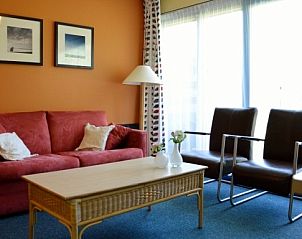 Stijlvolle zithoek in Appartment Amelander Kaap, Hollum, Ameland met warme kleuren en natuurlijk licht.