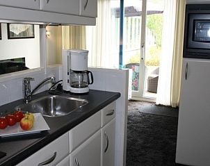 Volledig uitgeruste keuken in Appartment Amelander Kaap, Hollum, Ameland met moderne apparatuur en uitzicht op de tuin.