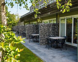 Privterras bij Appartment Amelander Kaap, Hollum, Ameland met zitgelegenheid en groene omgeving.