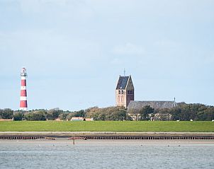 Iconische vuurtoren en kerk in Hollum, Ameland, nabij Appartment Amelander Kaap, met prachtig landschap.