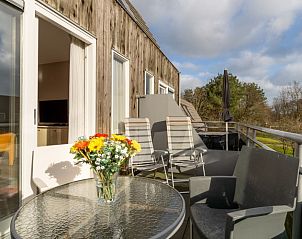 Zonnig balkon van Bornrif appartement, Hollum, Ameland met uitzicht op groene omgeving.