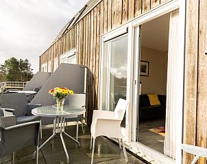 Ruim terras van Bornrif appartement, Hollum, Ameland met zitgelegenheid en bloemen.