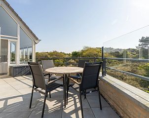 Zonovergoten terras van Zand appartement in Nes, Ameland, met uitzicht op duinen.