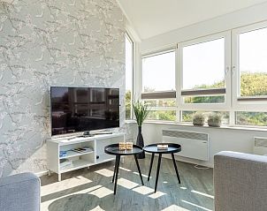 Zithoek in Zand appartement, Nes, Ameland, met grote ramen en uitzicht op natuur.