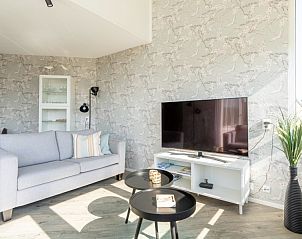 Comfortabele zithoek in Zand appartement, Nes, Ameland, met televisie en decoratieve accenten.