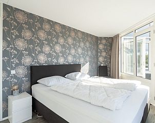 Hoofdslaapkamer van Zand appartement, Nes, Ameland, met modern behang en veel licht.