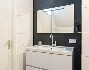 Stijlvolle badkamer in Zand appartement, Nes, Ameland, met moderne wastafel en spiegel.