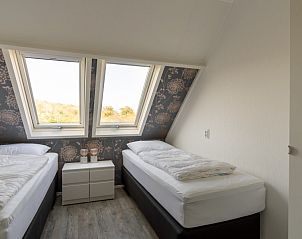 Tweede slaapkamer in Zand appartement, Nes, Ameland, met twee eenpersoonsbedden en dakramen.