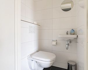 Netjes ingerichte toiletruimte in Zand appartement, Nes, Ameland, met witte tegels.