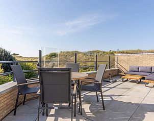 Ruim terras van Zand appartement, Nes, Ameland, met zitgelegenheid en uitzicht op duinen.