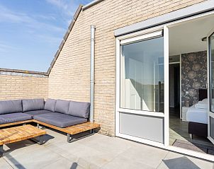 Privterras van Zand appartement, Nes, Ameland, met comfortabele loungebank.