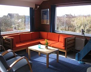 Gezellige woonkamer van In Het Dal vakantiehuis in Buren, Ameland, met uitzicht op de duinen.