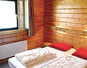 Sfeervolle slaapkamer met houten wanden in Ascona bungalow, Nes.