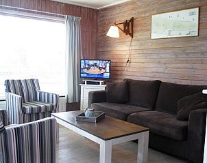Gezellige woonkamer van bungalow Klasina in Nes, Ameland met comfortabele zithoek en televisie voor ontspanning.
