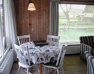 Eethoek in bungalow Klasina, Nes, Ameland met uitzicht op de tuin, perfect voor gezellige maaltijden op de Waddeneilanden.