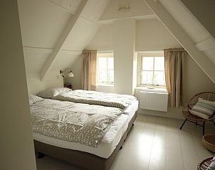Sfeervolle slaapkamer in Westhoek, Schiermonnikoog, met twee bedden en rustieke uitstraling.